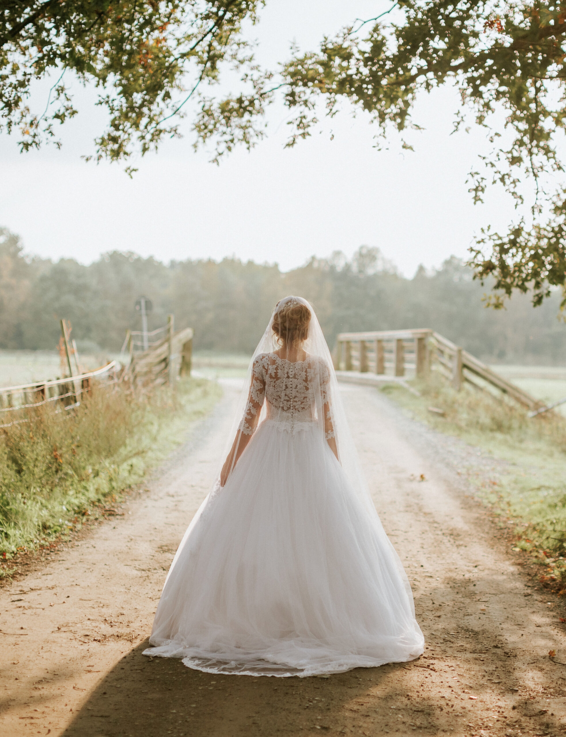 A bride walks down the road of her country estate wedding as her wedding photographer Beth Sheridan captures the scene.