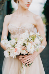 Bride in a beautiful dress holds a bouquet of flowers in her hands. High quality photo