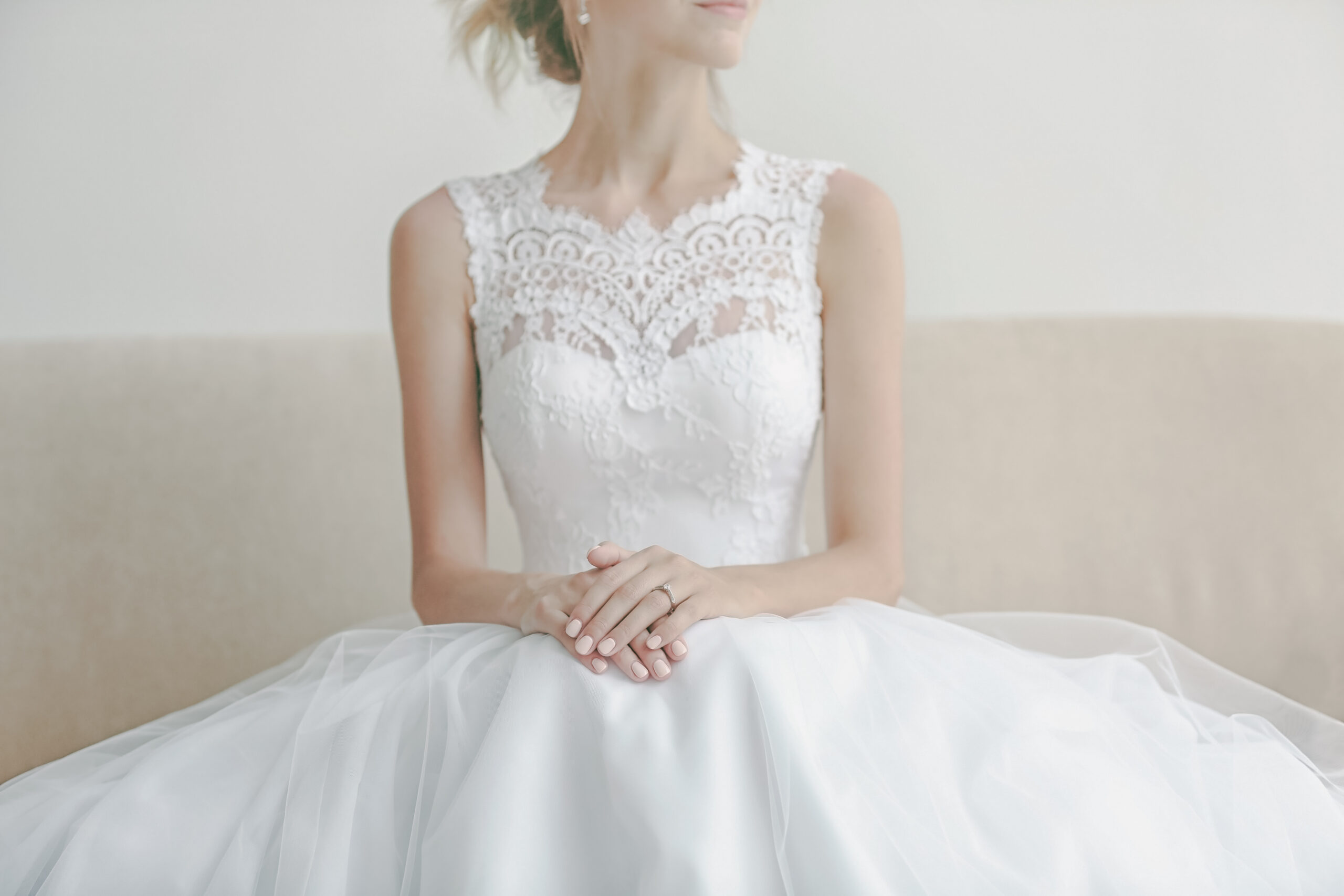 Houston bride in beautiful wedding gown sitting on sofa preparing for her Houston Destination Wedding.