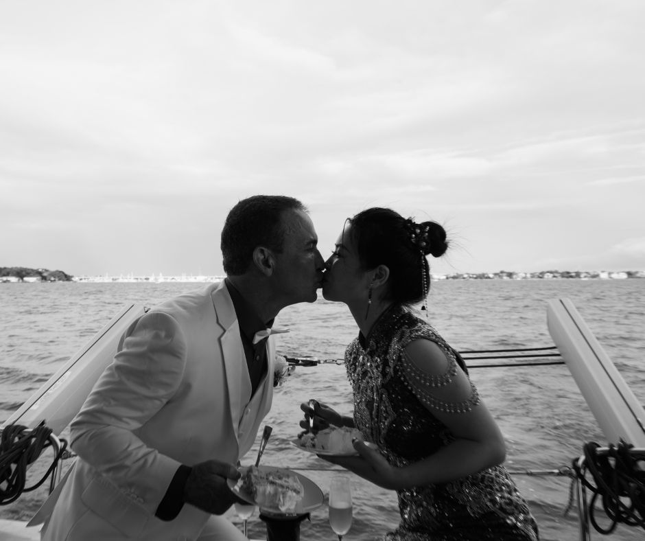 An elegant bride and groom share a kiss in a timeless black and white image taken during their Galveston, Texas sailboat elopement.