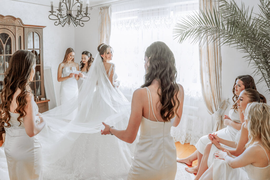 A bride and her bridal party enjoying an intimate, candid moment helping her to get ready for her luxury wedding.